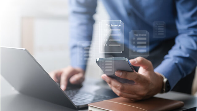 Business professional using laptop and smartphone with digital tax invoice icons, representing billing, VAT management, financial accounting, and electronic document handling for business compliance.