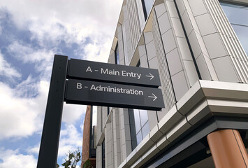 main entry and administration direction signs on the exterior of a modern building
