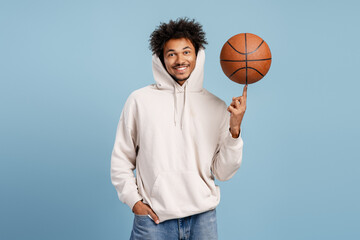 Happy young man spinning basketball on finger