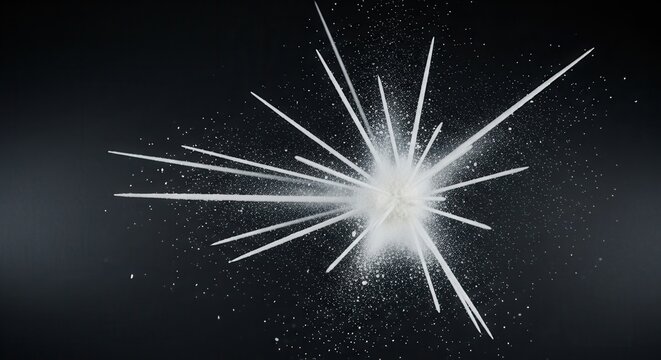 A vibrant white burst of fine particles erupts from a central point sending streaks and scattered dust across a dark backdrop