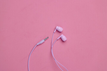 Wired purple earphones on a pink background