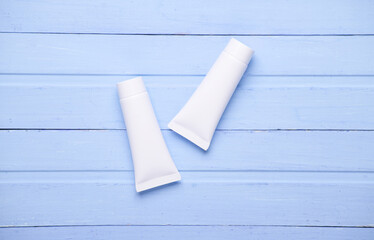 White cream tubes on blue wooden background. Template for design. Beauty concept