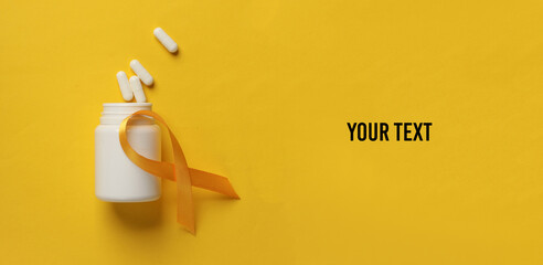 Pills with Yellow ribbon, childhood cancer awareness day symbol. Copy space for your text