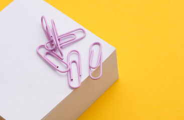 Stack of white memo papers with paper clips on yellow background