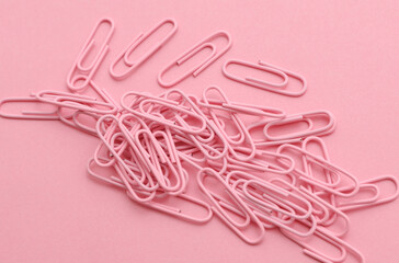 Pink paper clips on a pink background