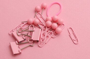 Stationery set of pink paper clips, binders, pins and rubber bands on pink background. Creative layout