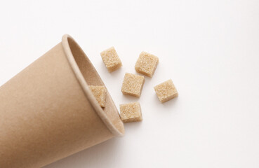 Cardboard cup with Cubes of cane brown sugar on white background