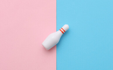 Miniature bowling pin on pink blue background. Conceptual photo. Top view
