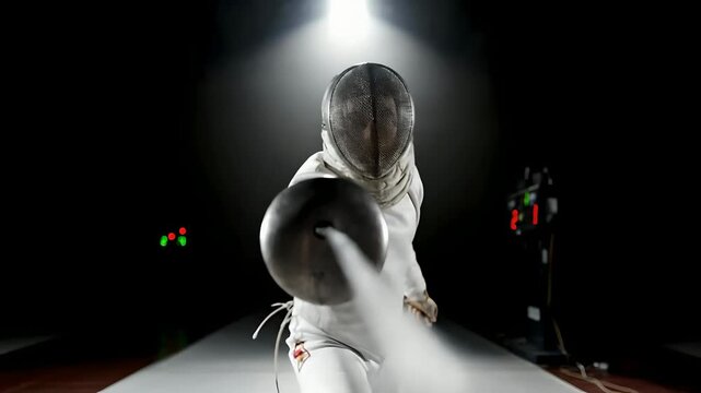 Fencer in White Uniform Lunges at Camera in a Dark Arena