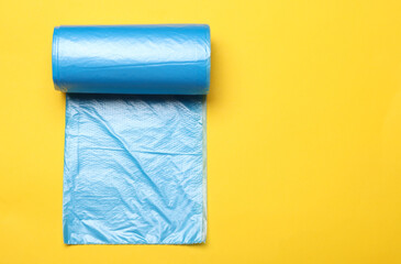 Roll of blue garbage bags on yellow background