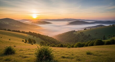 Fototapeta premium Golden sunrise illuminates lush green mountainsides with a valley filled by thick fog