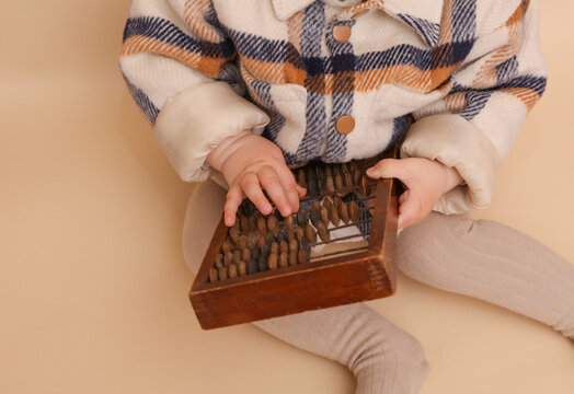 Little cute baby playing with abacus on beige background