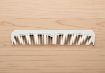 Pale Wooden Surface Showcasing a Sleek Modern White Hair Comb