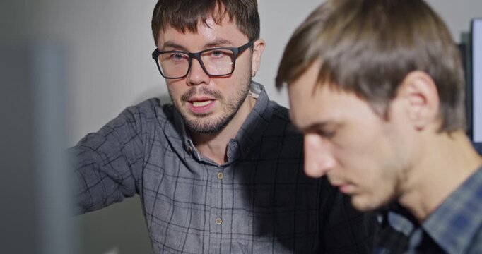 Closeup team adult male engineer collaborate on robotic hand project using AI code solutions machine learning at tech workspace. Artificial intelligence interface, collaboration prototype development.