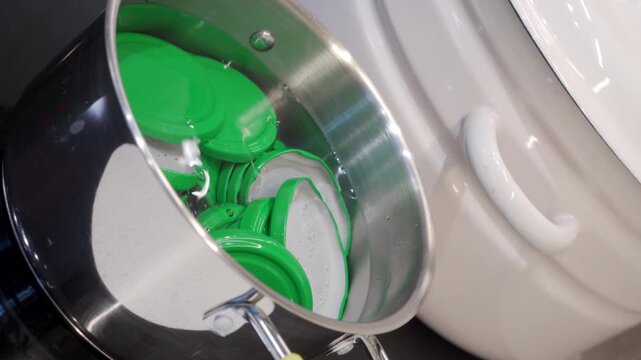 Vibrant green canning lids are immersed in boiling water within a metal pot, a vital sterilization step. This meticulous preparation on an induction hob ensures hygiene for homemade food preservation.
