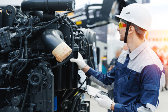 Mechanic engineer with tablet computer inspecting and fix engine from industrial mining truck, diesel injector adjustment and filter replacement