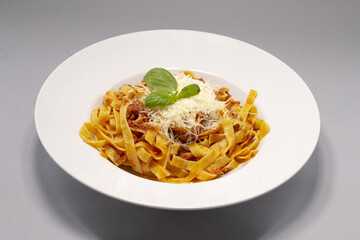 A delicious plate of fettuccine pasta beautifully topped with fresh cheese and aromatic basil leaves