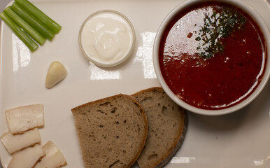 The arranged plate features a steaming soup, warm bread, and vibrant garlic and celery, making an appetizing display