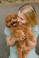 Woman cuddling poodle outdoors with smile