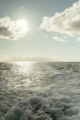 Fototapeta premium Sunlit ocean wake off the coast of Maui under cloudy sky