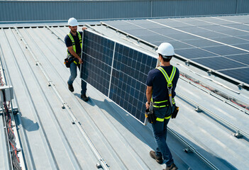 professional workers installing photovoltaic solar panels on a metal rooftop under clear skies. 