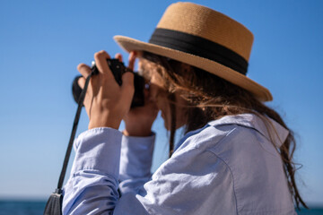 Obraz premium Photographer, camera, woman taking pictures outdoors with a straw hat and blue shirt under clear sky.