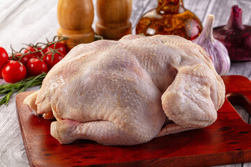 Raw whole chicken over board