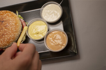 The image prominently features a delicious hamburger topped with various sauces, alongside a side of fries