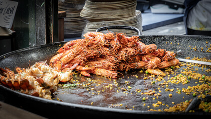 A large paella pan with grilled prawns, lobster and rice.