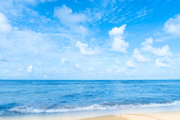 Sea beach sand with soft waves and blue sky with fluffy clouds. Peaceful Scenic tropical summer seascape ideal for vacation, travel ads, resort promotions, nature backgrounds, or relaxation themes.