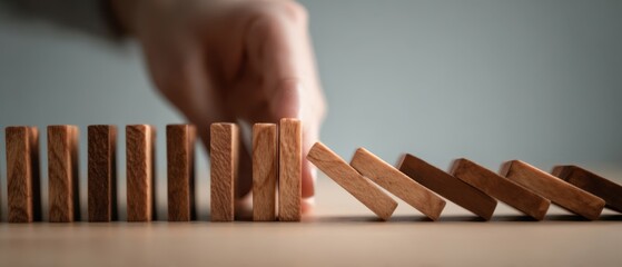 The Wooden Dominoes Falling as a Hand Stops the Chain Reaction