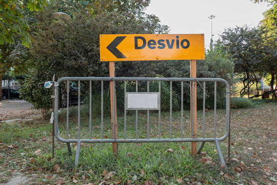 Sinal de aviso de desvio com a descri&ccedil;&atilde;o em portugu&ecirc;s "Desvio" apoiado num cavalete de madeira e bloqueado por uma barreira met&aacute;lica num ambiente exterior e arborizado