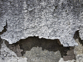 Aged gray texture of peeling stucco wall. Abstract background of old, damaged concrete surface, showing decay, crack, and weathered plaster material with grunge effect