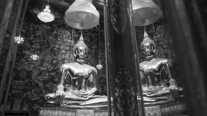 Serene black and white view of golden Buddha statue in spiritual temple. This sacred sculpture for meditation and religion evokes feeling of calm and ancient tradition
