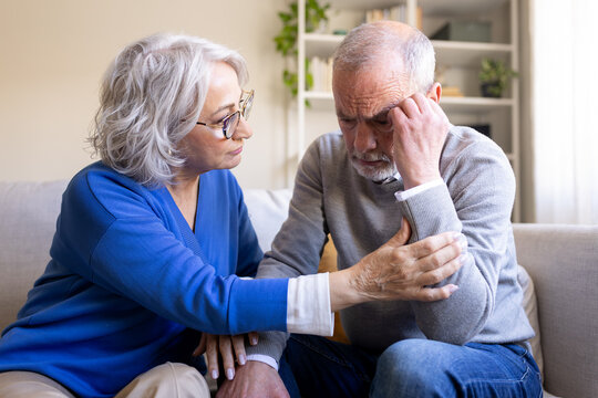 Senior woman comforting her sad husband at home
