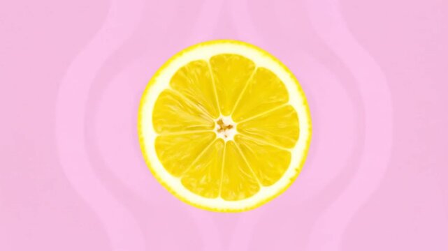 Vibrant lemon slice against a pastel pink background