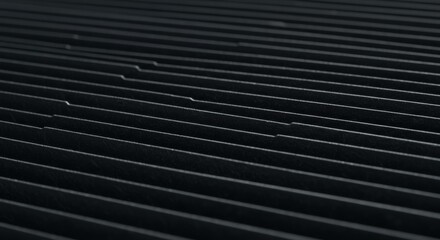 Black textured surface with parallel lines and subtle reflections  