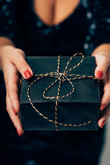 Woman's hands holding elegant black christmas gift box
