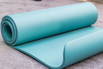  Blue yoga mat rolled up on floor, fitness equipment for exercise, workout, stretching and home training