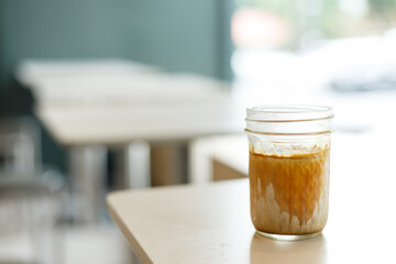 Cup of chilled milk dirty coffee on table by the window. Selective focus.