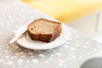 Moist Peanut butter Banana bread sliced with sauce on ceramic plate by the window.