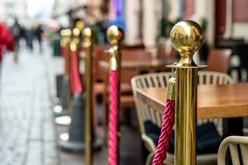 Golden stanchions with red ropes outside a stylish cafe