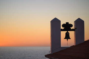 Bell on top of a small church in Carvoeiro at the Algarve coast in Portugal. Taken at dusk with the Atlantic Ocean in the background. © Christoph
