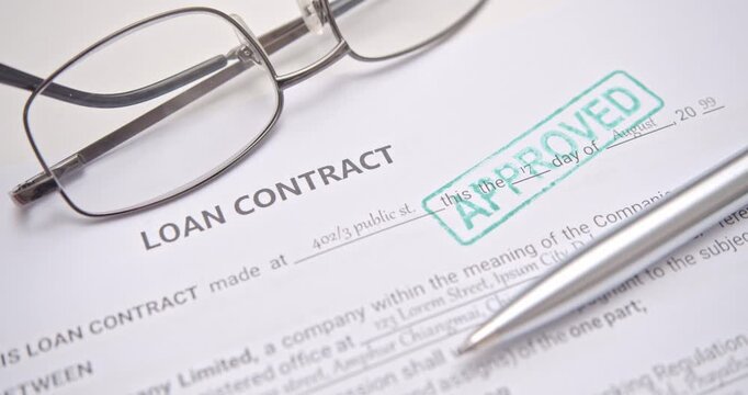 Macro shot of a signed loan contract form with &ldquo;APPROVED&rdquo; stamp and pen, representing finance approval, credit validation, and successful loan agreement in the banking sector.