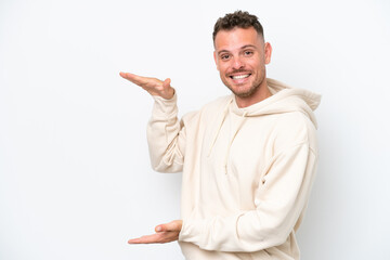 Young caucasian handsome man isolated on white background holding copyspace to insert an ad