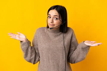 Young telemarketer woman isolated on yellow background having doubts while raising hands