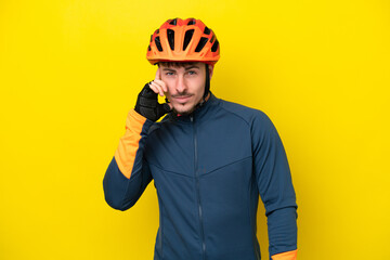 Young cyclist caucasian man isolated on yellow background thinking an idea