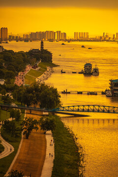 The Yangtze River and its shipping vessels, bathed in the glow of the setting sun, are located in Jiujiang, a historical and cultural ancient city in eastern Asia, Jiangxi Province, China.