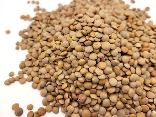 Bigger pile of brown lentils against a bright background