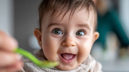 Happy baby enjoying food with a green spoon in a bright kitchen during lunchtime